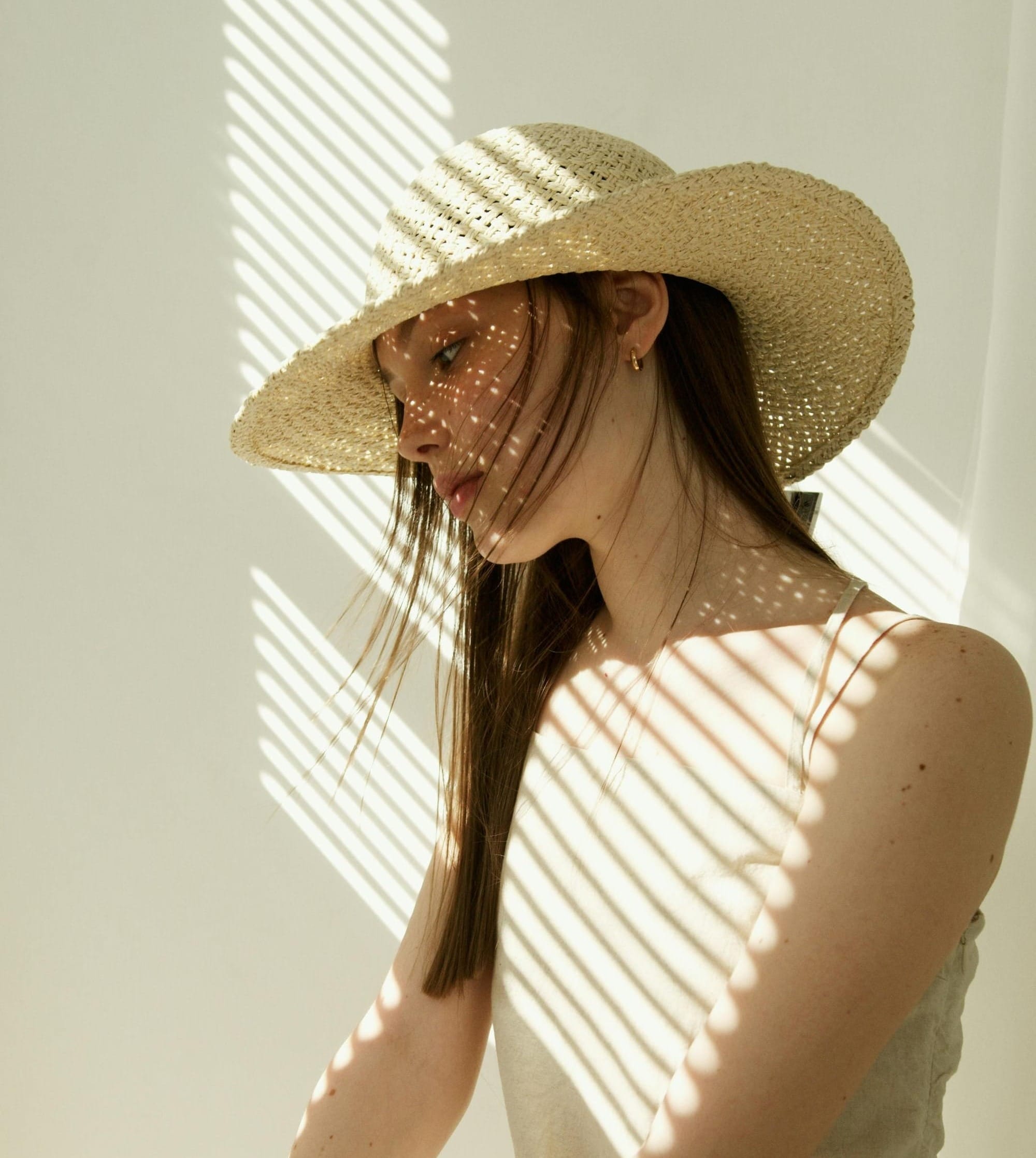 Woman in pastel summer dress, long hair and big straw sun hat