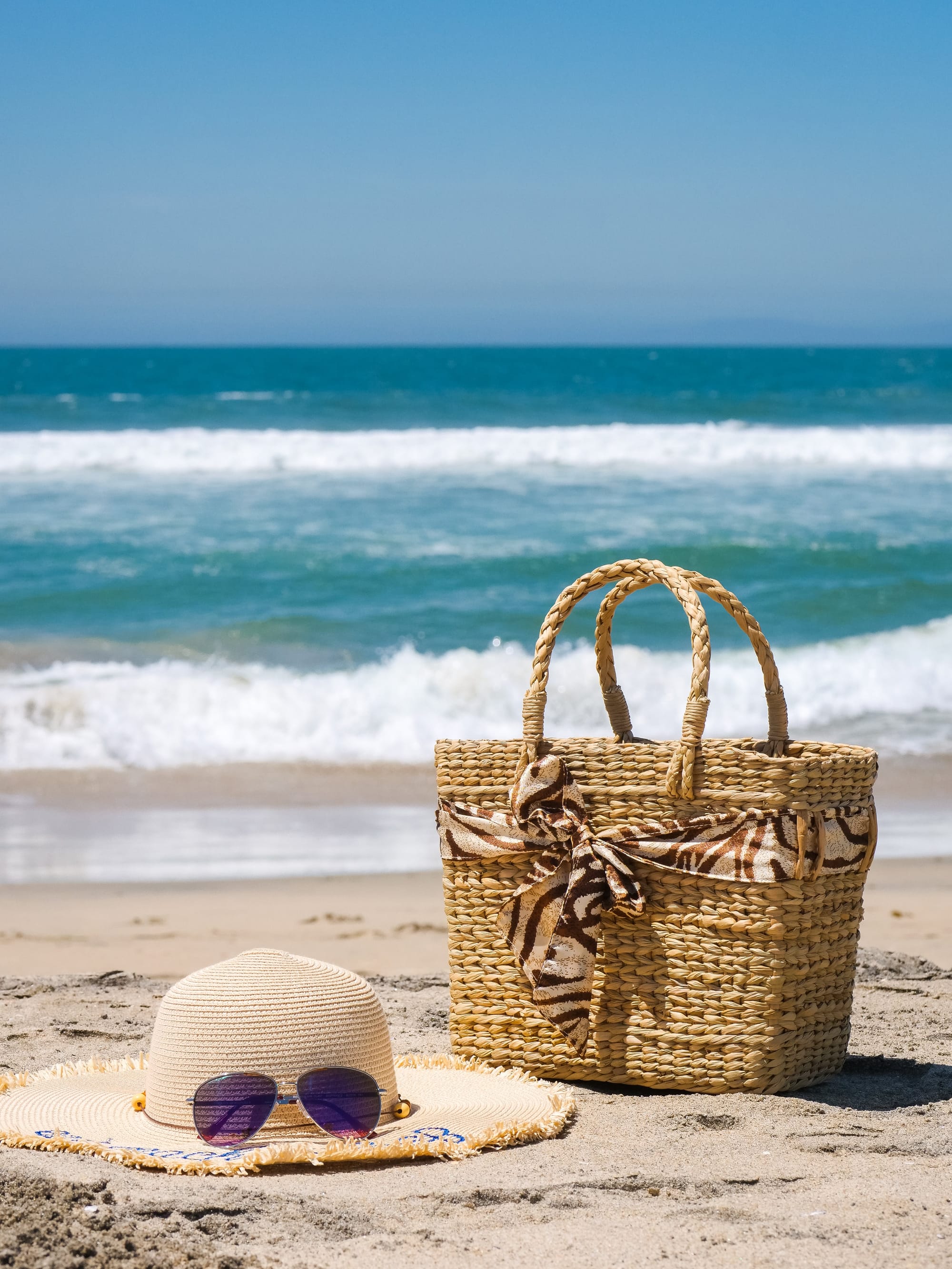 Straw hat, sunglasses and straw bag on the beach