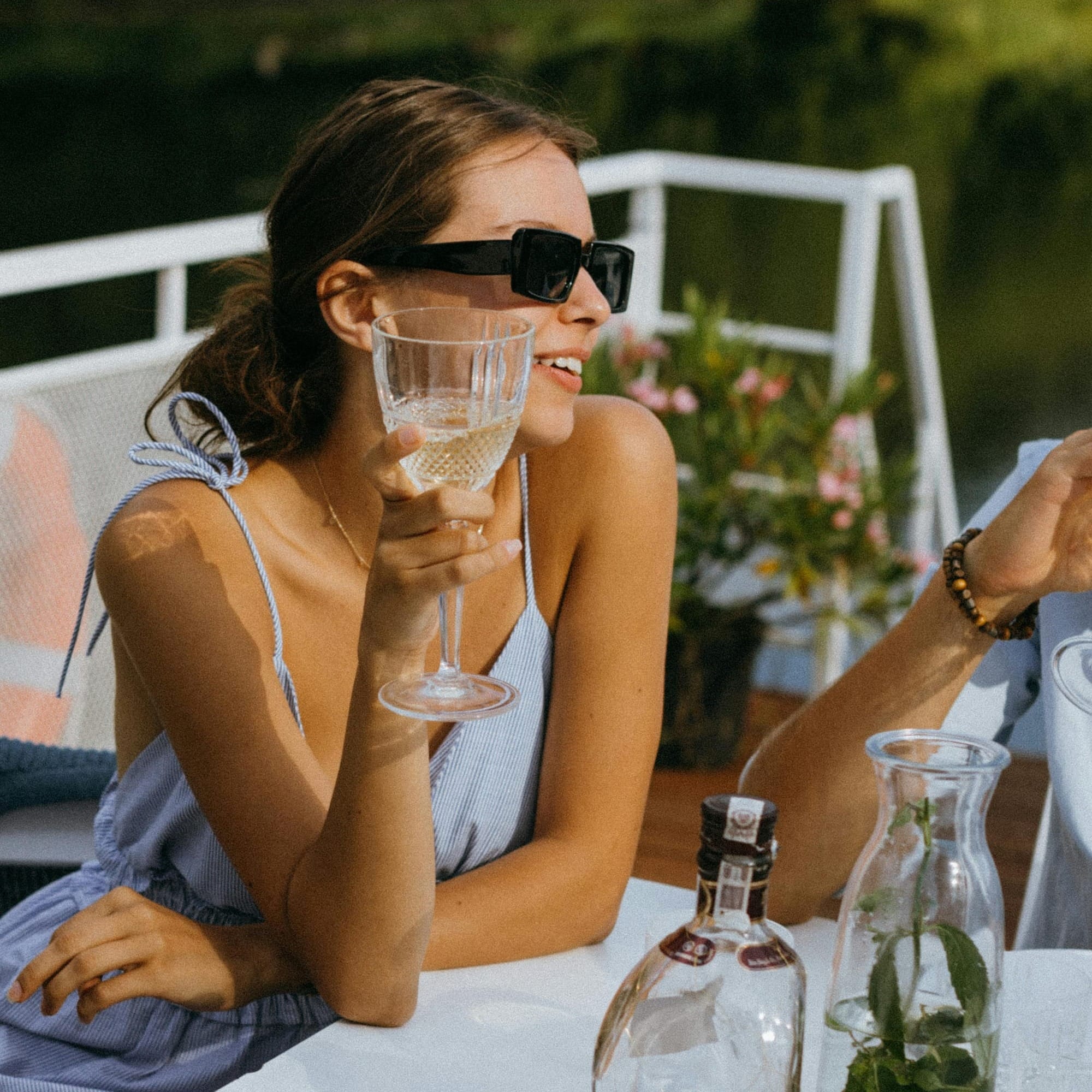 Woman behind a outdoor restaurant table wearing cool black rectangular sunglasses